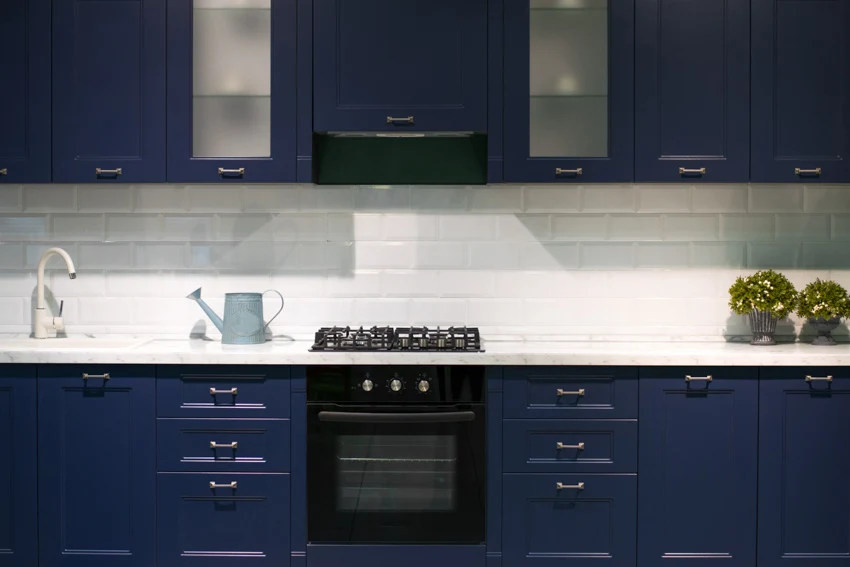Blue kitchen cabinets white backsplash black oven