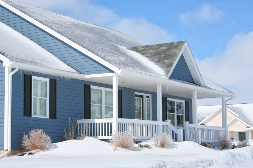 Blue siding house covered in snow front porch