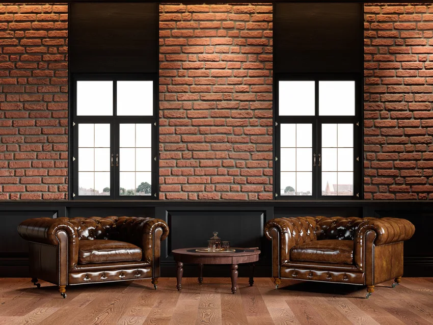 Brick wall black windows brown leather couches wood flooring coffee table
