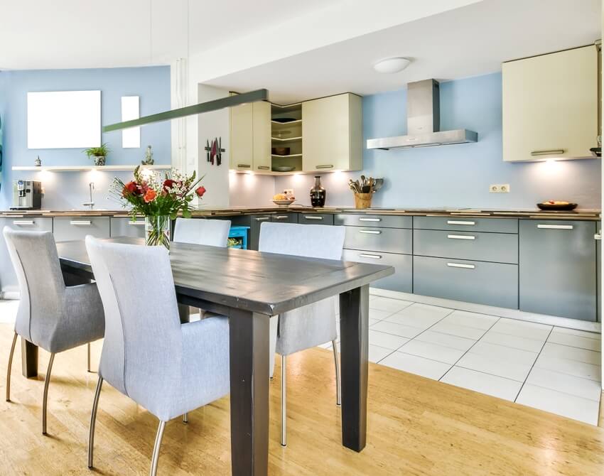 Bright kitchen with different cabinet colors and dining room with decorative table and chairs