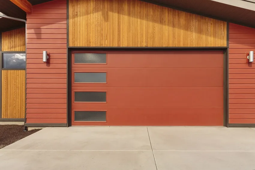 Bright red garage doors with decorative windows light fixtures and a side gate