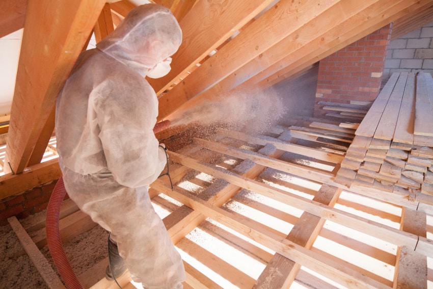 Contractor applying insulation in attic