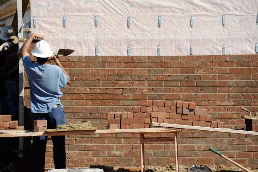 Contractor installing brick masonry veneer