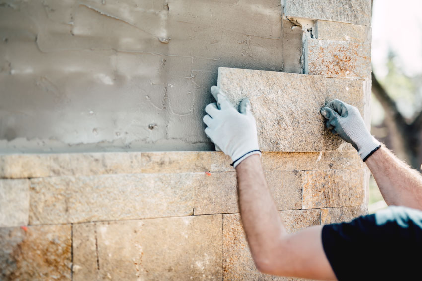 Contractor laying masonry stone on exterior