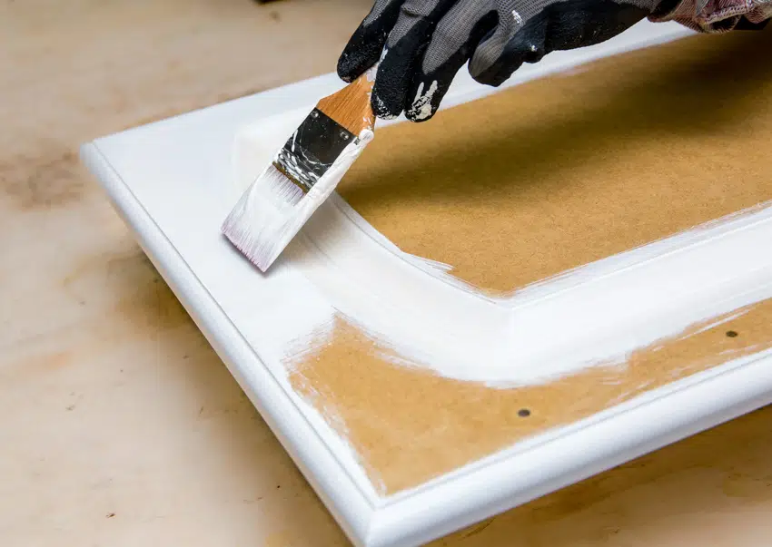 Contractor painting cabinet door with thermofoil