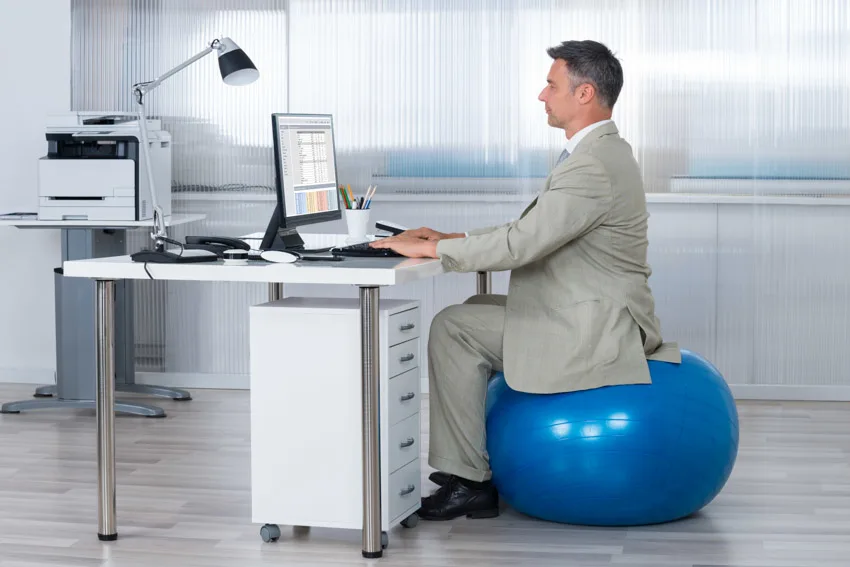 Employee sitting on exercise ball computer desk