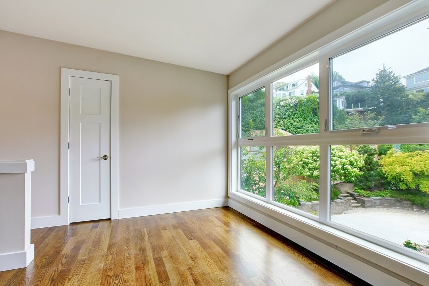 Empty hallway interior in white tones with hardwood floor and big windows