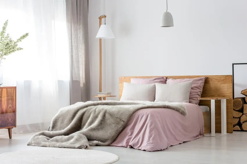 Fluffy grey blanket on wooden bed with pink bedding