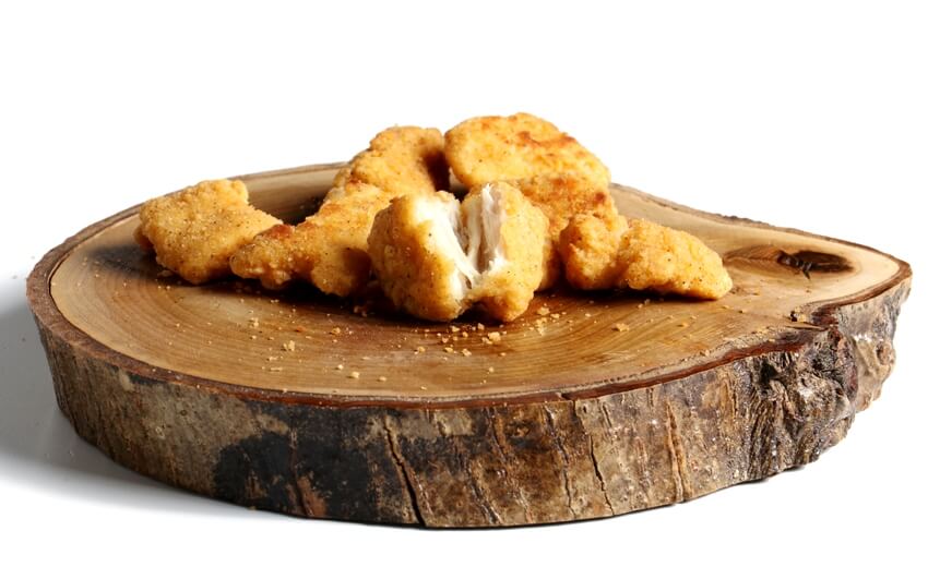 Fried crispy chicken nuggets on hardwood cutting board