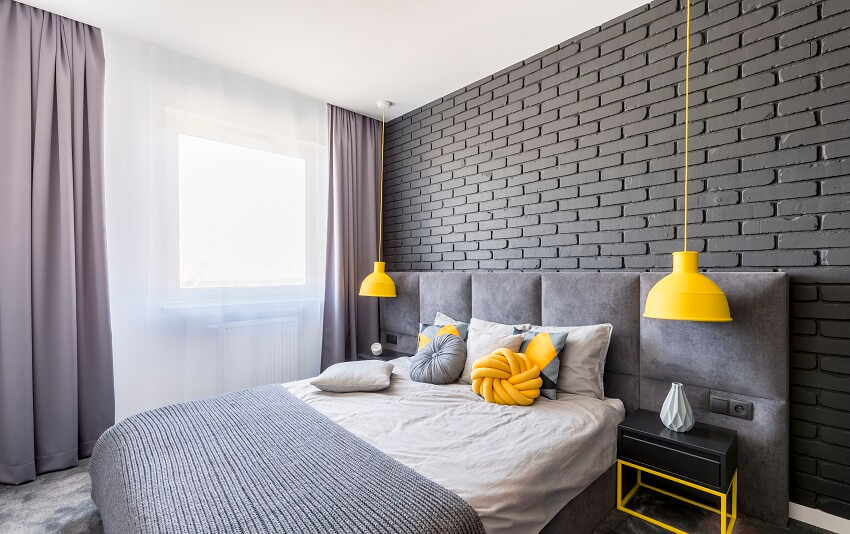 Gray and yellow bedroom interior with window with curtains brick wall two lamps and knot cushion