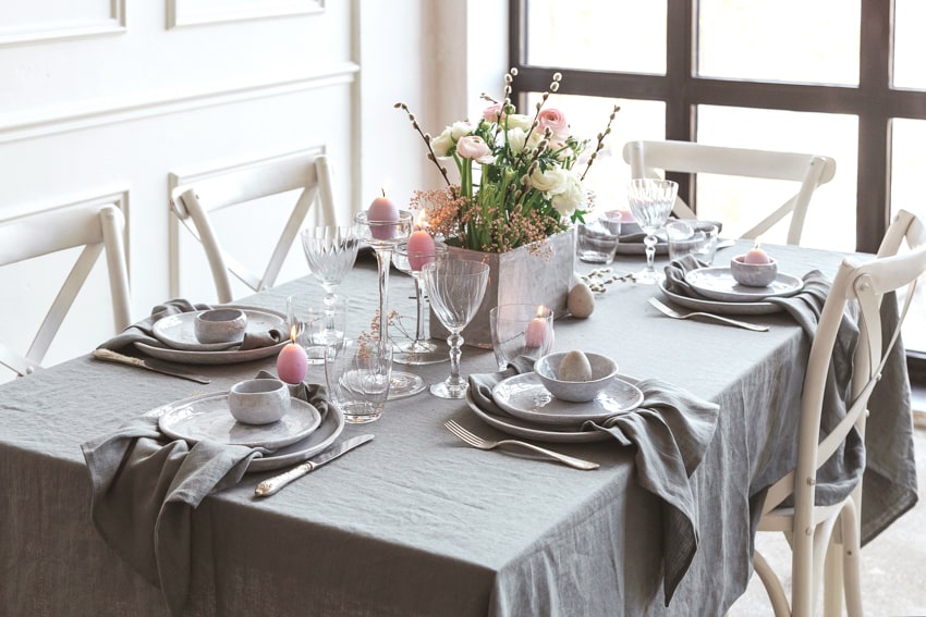 Gray tablecloth with white chairs, plates and flowers