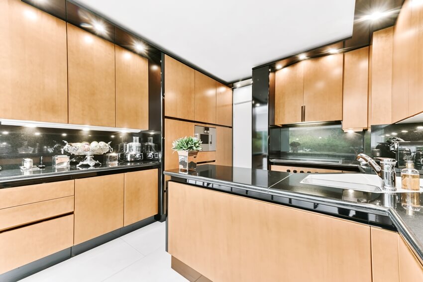 Interior of a beautiful kitchen with wooden cabinets black granite countertops and accents