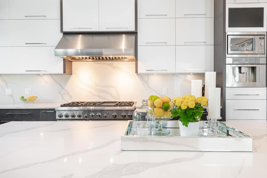 Kitchen quartz backsplash stove hood countertop center island white cabinets