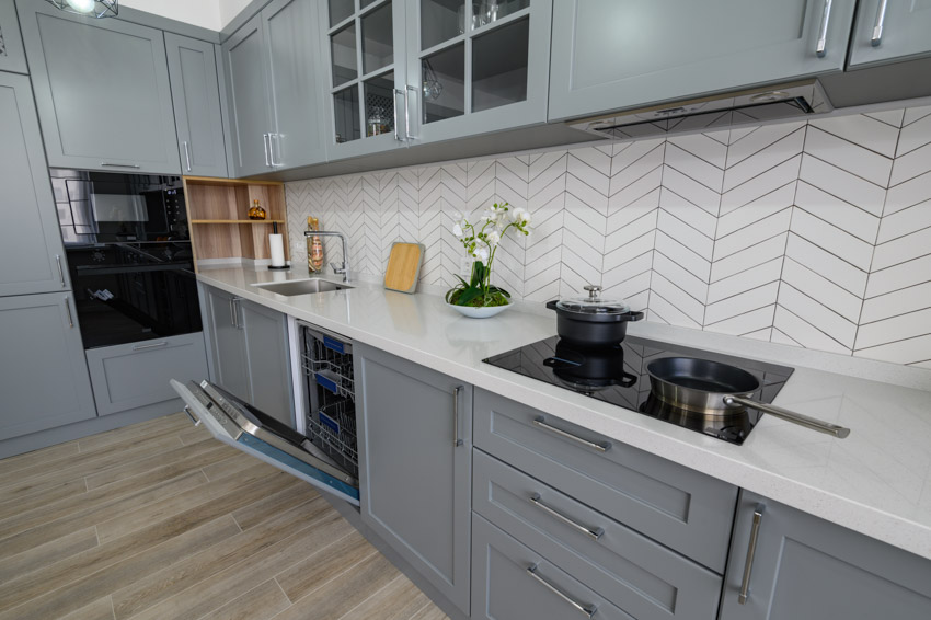 Kitchen with gray cabinets white herringbone backsplash oven wood floors