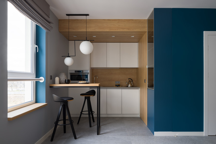 Kitchen with small island white cabinets blue wall hanging lights