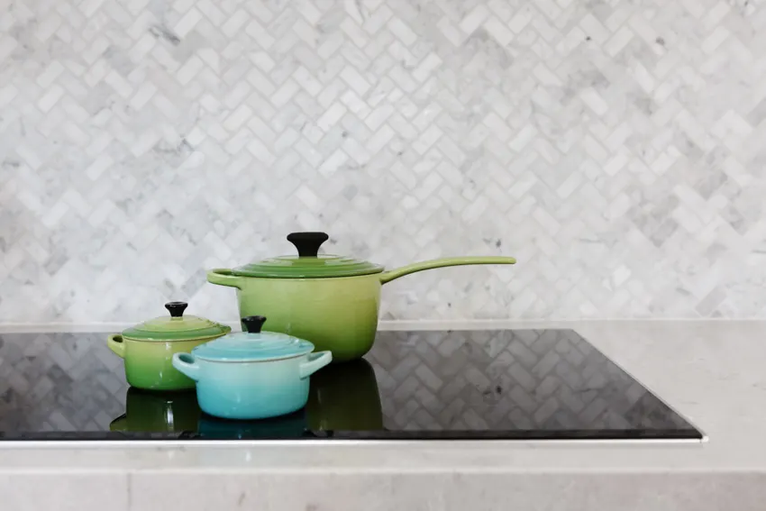 Kitchen with tile herringbone backsplash induction stove countertop