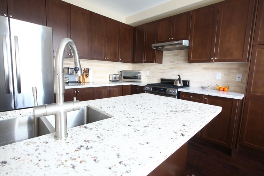 Kitchen with wood cabinets quartz tile backsplash countertop with sink and faucet