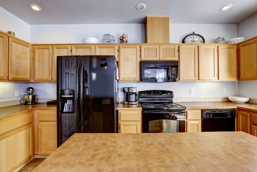 light brown kitchen cabinet with black appliances