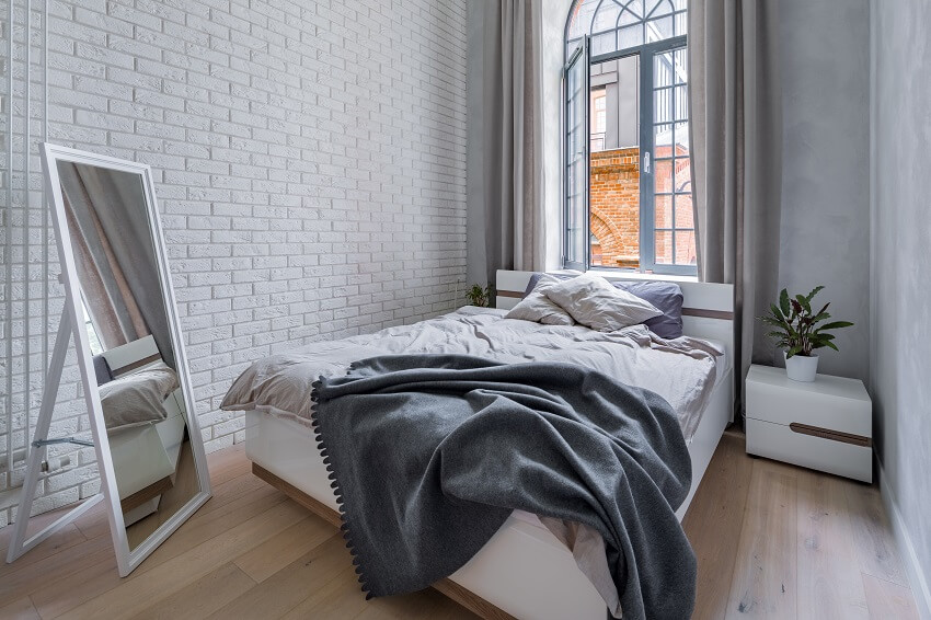 Loft bedroom with white brick wall double bed and mirror
