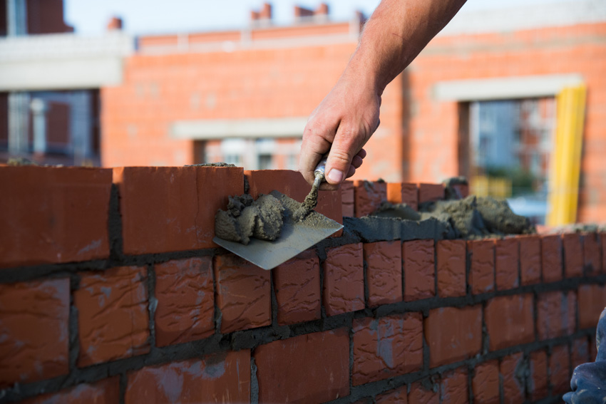 Man laying down red bricks