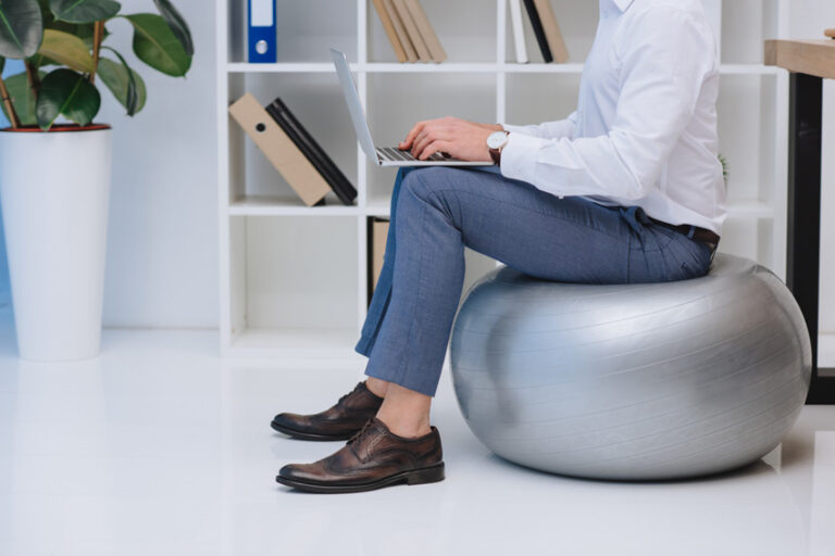 Man Sitting On Exercise Ball While Working Shelf White Floor Is 768x512 