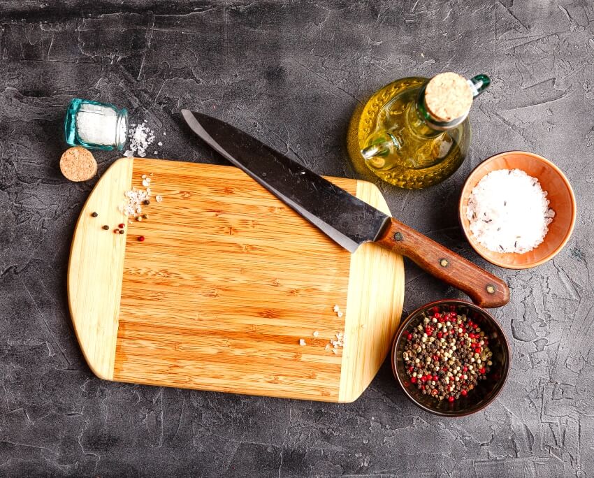 wood board with olive oil salt pepper and knife on on the side
