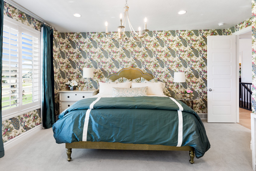 Bedroom with patterned walls and bed with green sheets and curtains