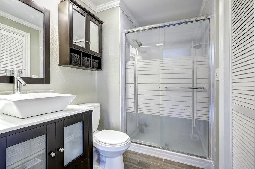 Modern bathroom interior with glass door, shower waterproof bathroom paint, brown vanity cabinet with white vessel sink and mirror