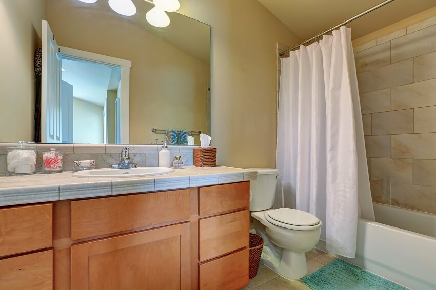 Modern bathroom vanity cabinet with drawers and marble top full bath shower with white curtain and a toilet