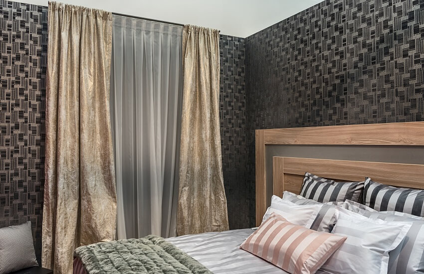 Modern design of bedroom with natural materials dark walls with a geometric pattern bed linen in stripes and straight vintage curtains