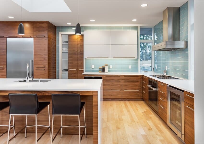 Modern kitchen in new contemporary style luxury home with island pendant lights hardwood floors stainless steel appliances and blue tone tile that extends to the ceiling