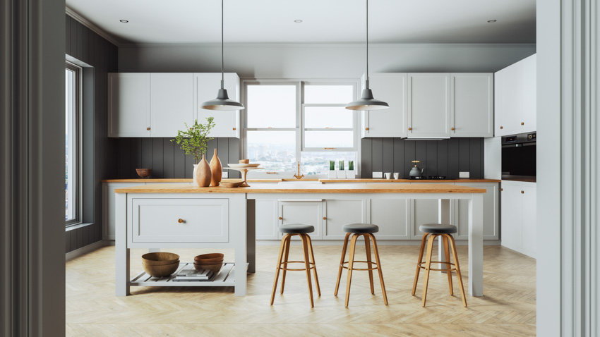 Kitchen with gray painted shiplap walls and long island with a floating slab of wood countertop