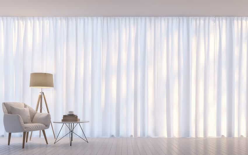 Modern white living room decorated with white translucent curtain and white armchair