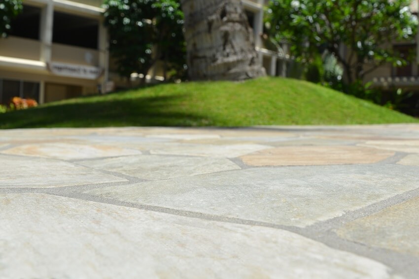 Multi colored geometric tile flooring outdoors with tree and building