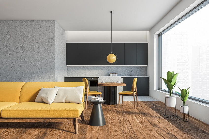 Open space home interior with yellow sofa, coffee table on parquet floor, black kitchen set, dining table with chairs