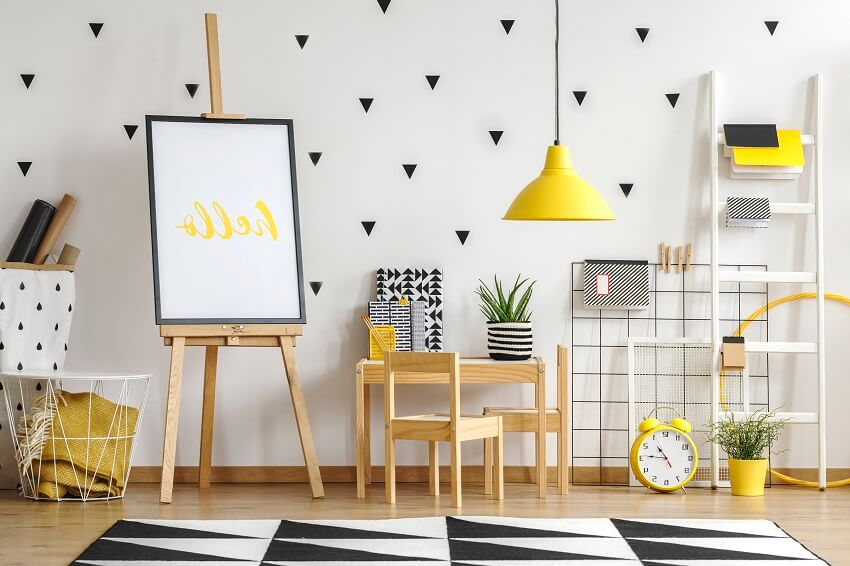 Playroom and study corner interior with wooden furniture yellow lamp and black stickers on a white wall
