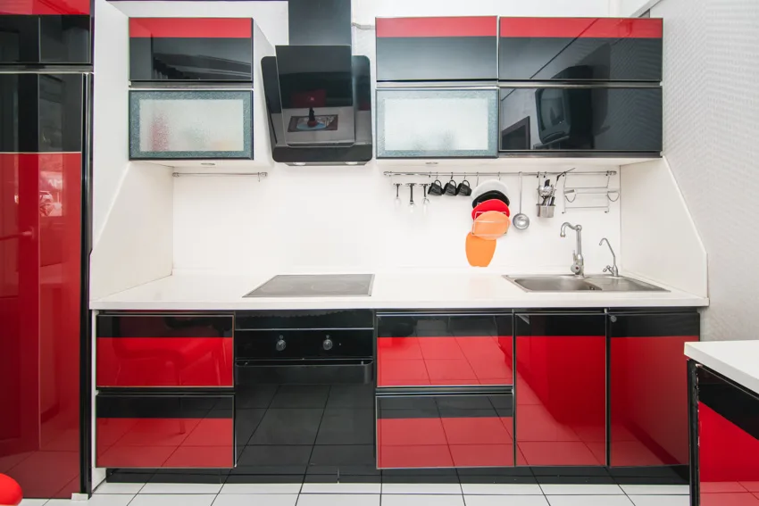 Red kitchen cabinets white tile flooring black oven and hood