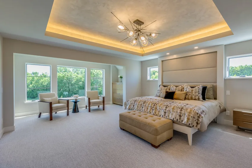 Spacious master bedroom with padded headboard recessed lighting windows