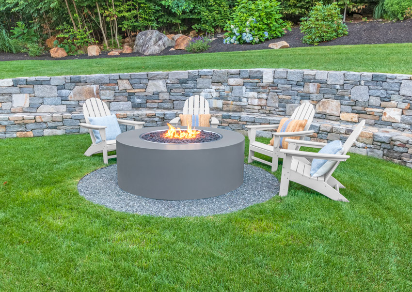 Stone wall around modern fire pit with gravel surround