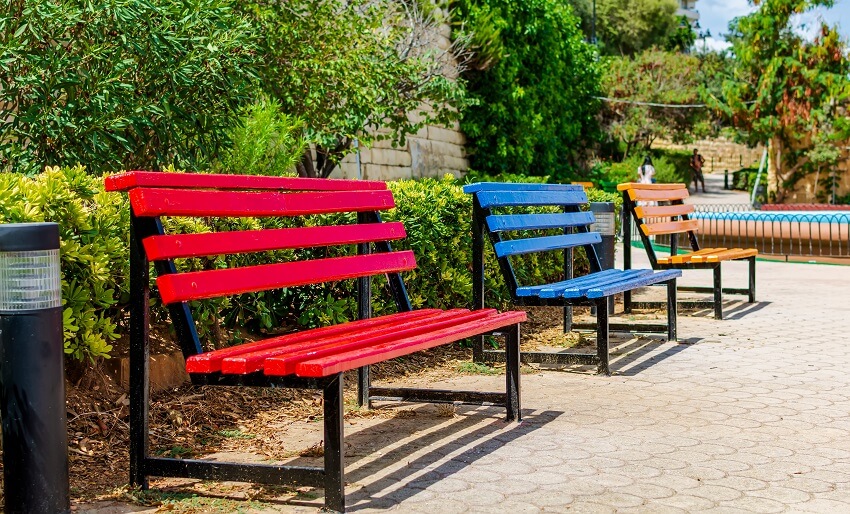 Three multicolored benches red blue and yellow in a park