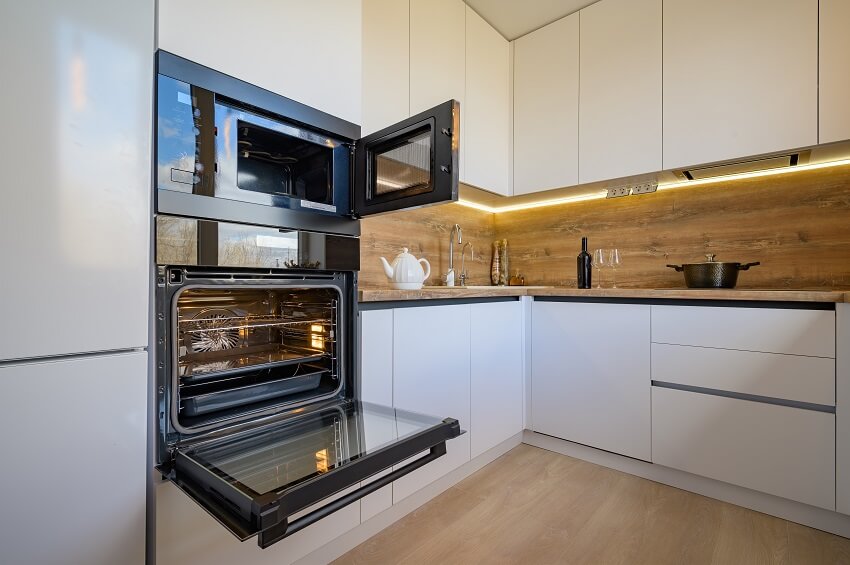 Well designed white and wooden beige modern kitchen interior with oven door opened