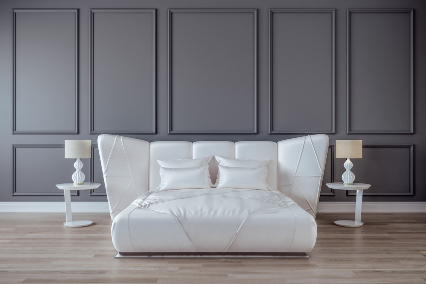 White bed with silk sheets black wall wood floor bedroom