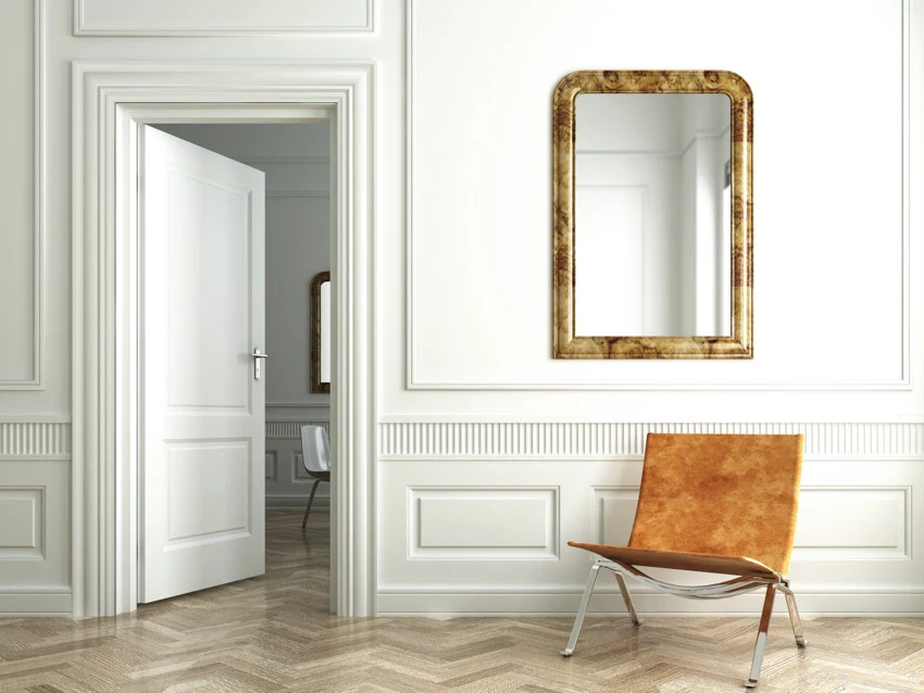 White wall baseboard wood floor mirror door orange chair 