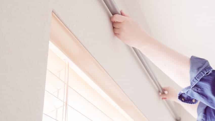 Woman hanging curtains in bedroom at new house