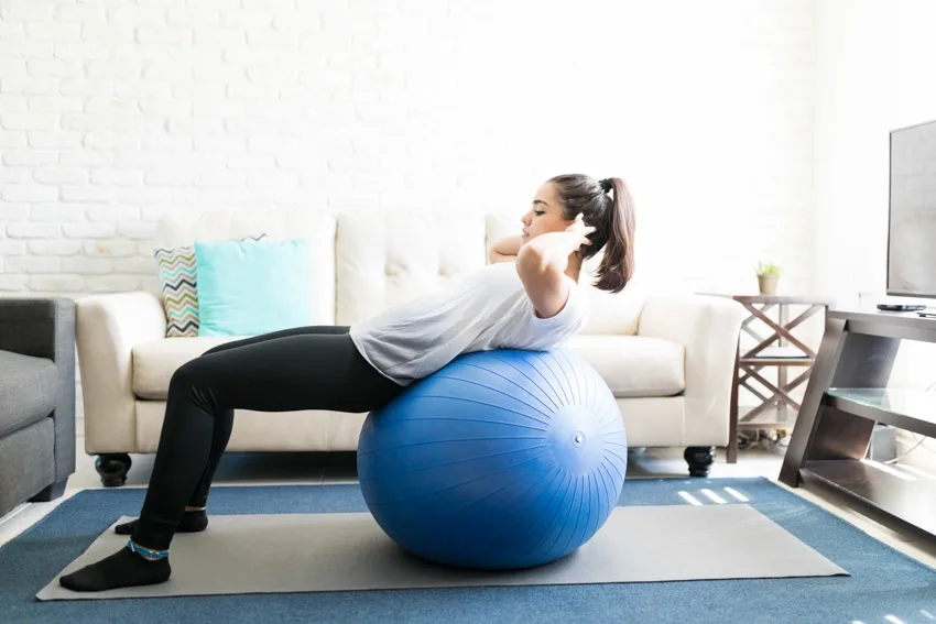 Woman working out on exercise ball rug living room couch