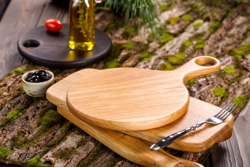 Wooden oak cutting board on rustic wooden background with bark