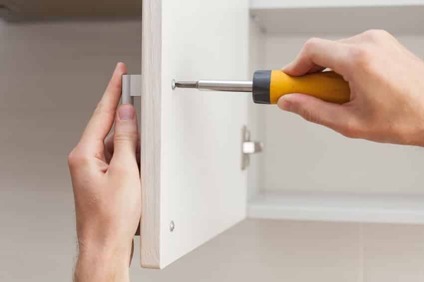 Worker sets a new handle on the white cabinet