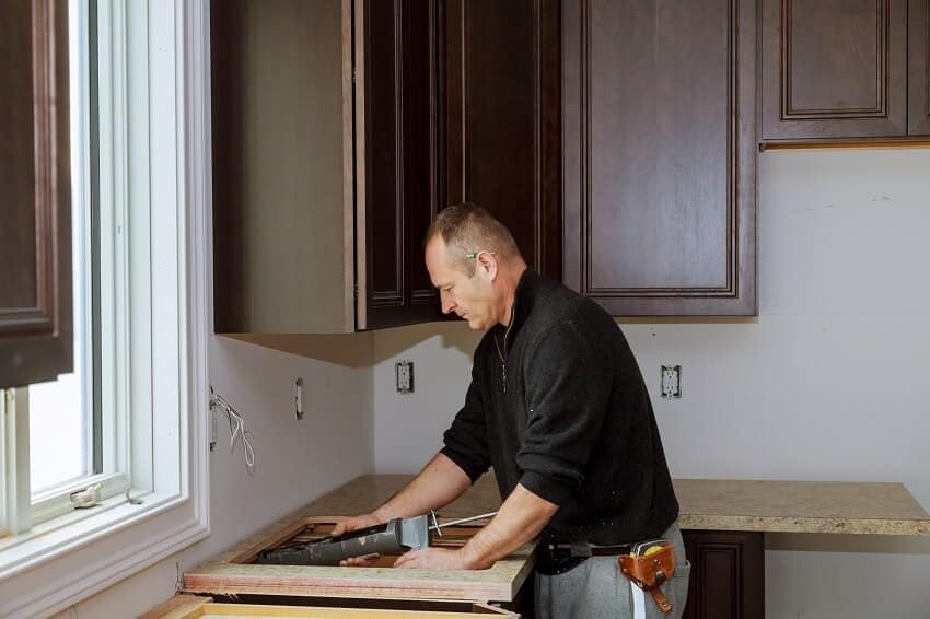 A kitchen carpenter installing veneer countertop with a sink