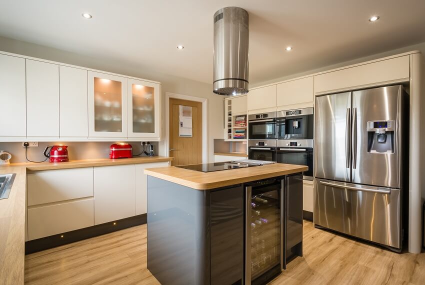 A modern kitchen with high gloss units rounded corners island and wooden countertop and flooring