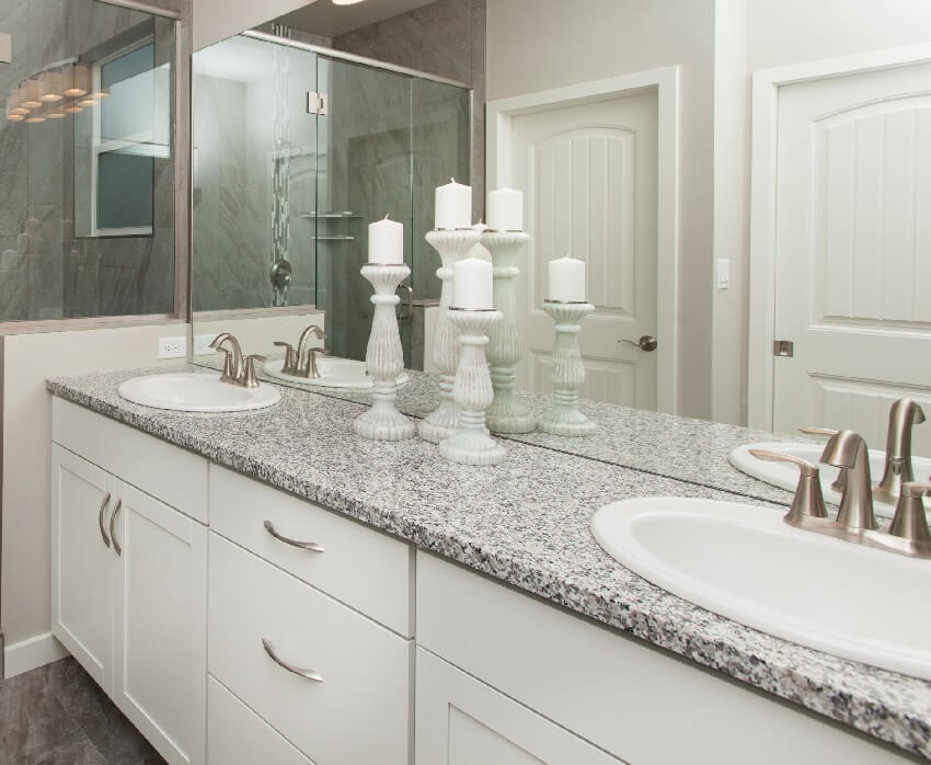 Bathroom with composite marble countertop with white drawers and a mirror